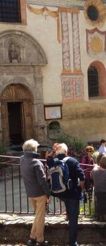 Hauteluce, l'été. Un groupe de personnes devant l'église et ses fresques extérieures