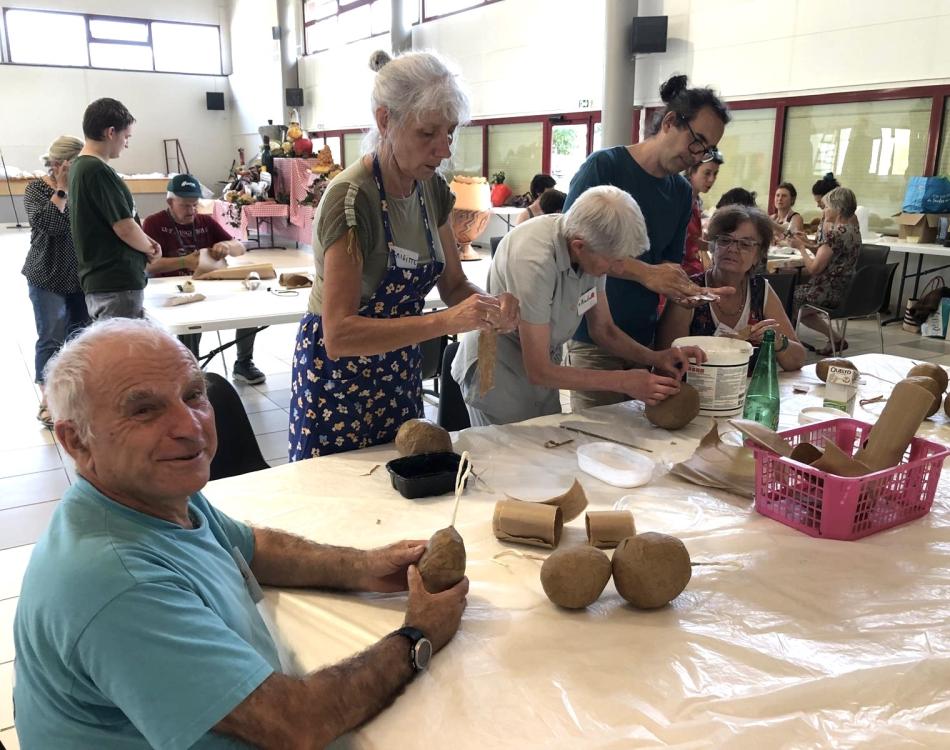 Autour d'une table, des personnes de tous âges réalisent des accessoires pour le spectacle Un appétit de géants