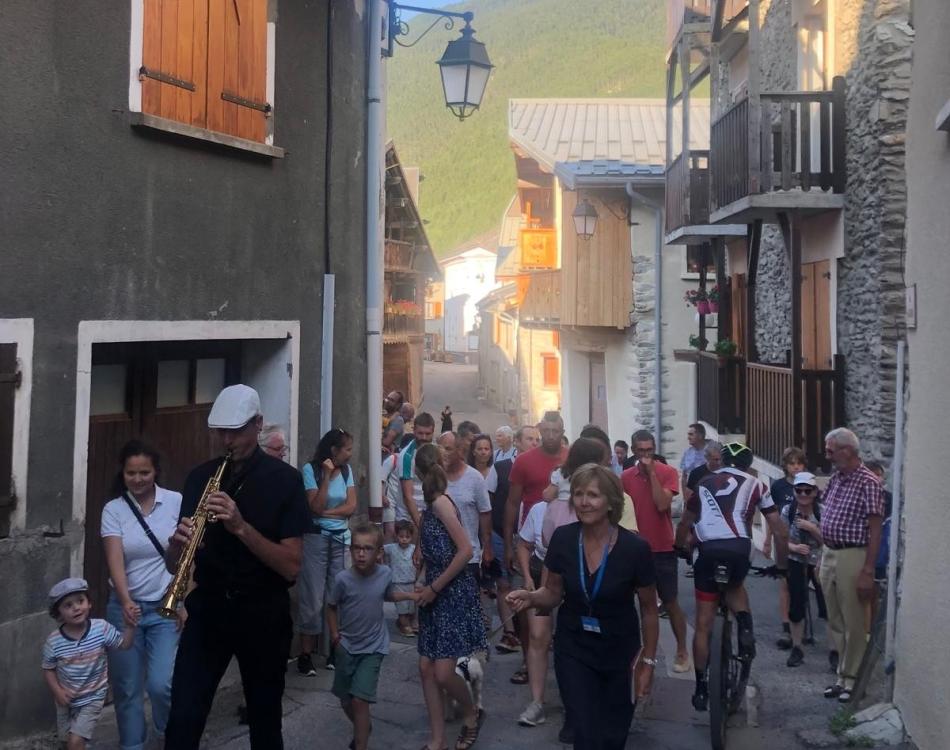 Un musicien entraîne le public dans les rues de Bramans. Barock n'roll, Escapades baroques dans les Alpes avec la Fondation Facim