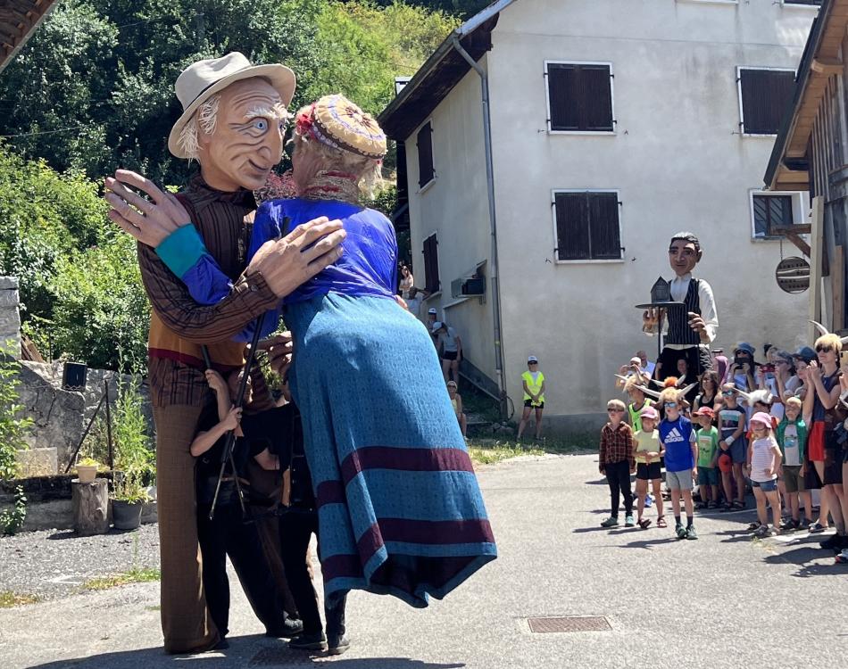 Deux marionnettes géantes dansent devant le public à La Compote en Bauges