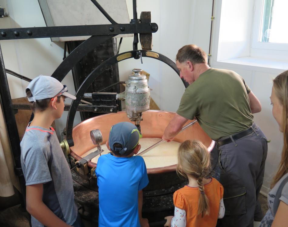 Un agriculteur montre la fabrication du fromage entouré d'enfants