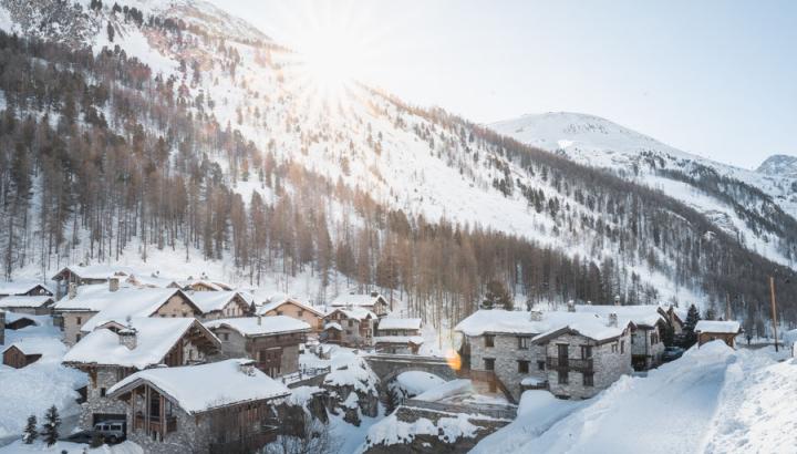 Le Fornet - Val d'Isère - Magnifique vue du typique hameau du Fornet sous la neige. Le soleil commence à se cacher derrière le versant de la montagne et illumine les maisons en pierre du village.