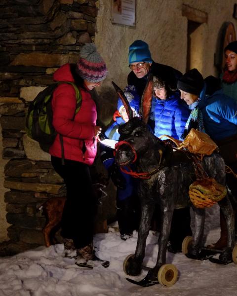 Groupe d'adultes et d'enfants dans un village enneigé autour d'un âne à roulettes