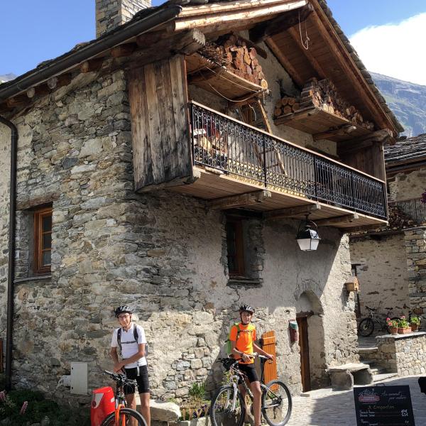 Deux jeunes garçons à vélo devant un chalet ancien. Escapades baroques dans les Alpes avec la Fondation Facim