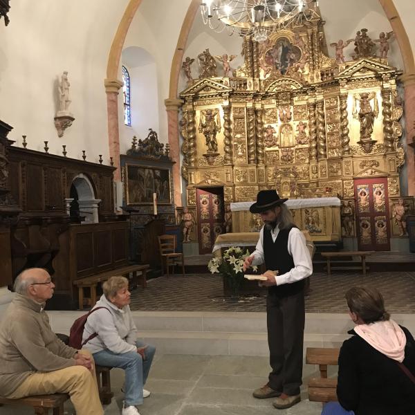 Un guide en costume d'époque montre un objet au public dans une église baroque. Escapades baroques dans les Alpes avec la Fondation Facim